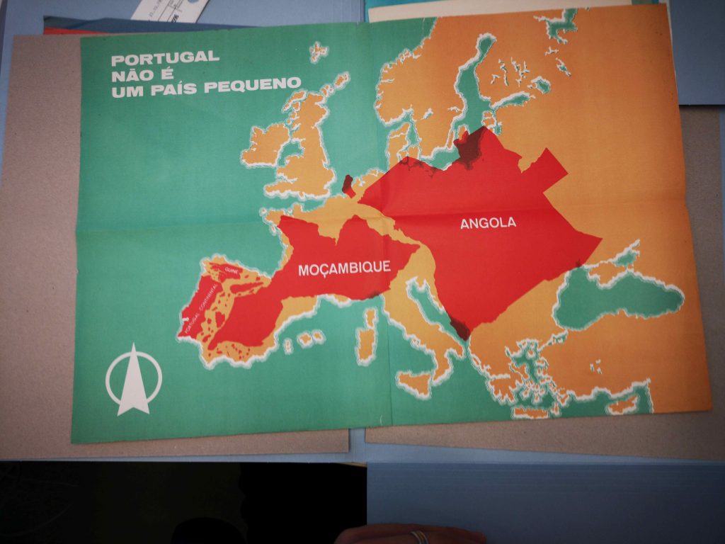 Propaganda-Poster, das den Umfang von Mozambik und Angola auf eine Karte Europas projiziert. Schrift: Portugal nao e um pais pequeno. Materialien aus der Bibliothek des Ibero-Amerikanischen Instituts.